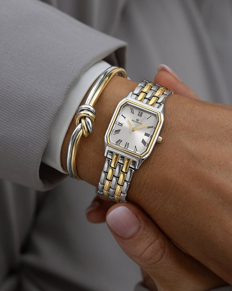 A square women’s watch and double knot bracelet in gold and silver from Waldor & co. The model is Eternal 22 Bellagio & Dual Knot Bangle.