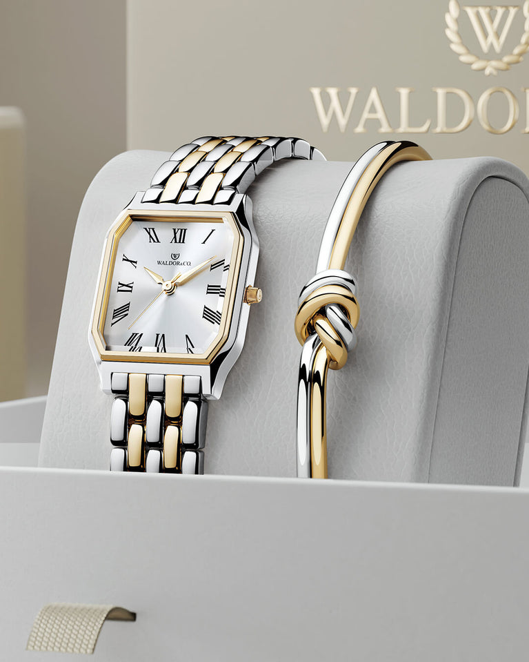 A square women’s watch and double knot bracelet in gold and silver from Waldor & co. The model is Eternal 22 Bellagio & Dual Knot Bangle.