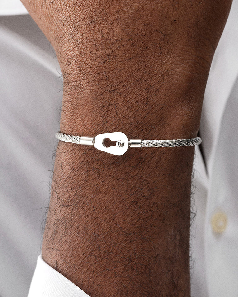 A polished stainless steel bangle in silver from Waldor & Co. One size. The model is Como Bangle Polished