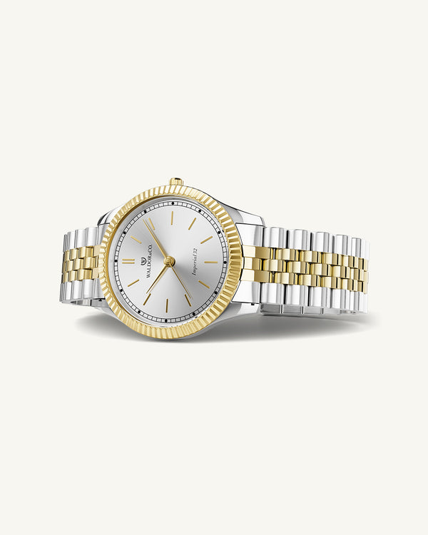 A round womens watch in silver and 22k gold from Waldor & Co. with silver sunray dial and a second hand. Seiko movement. The model is Imperial 32 Positano 32mm.