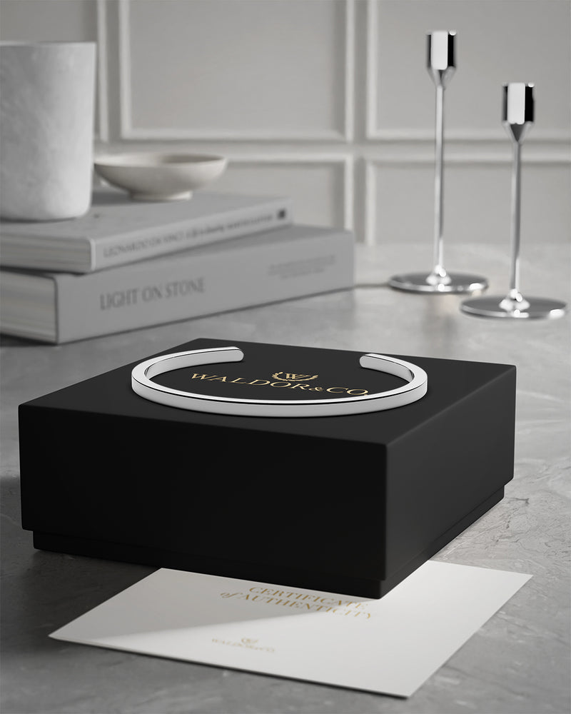 A polished stainless steel bangle in silver from Waldor & Co. One size. The model is Square Bangle Polished