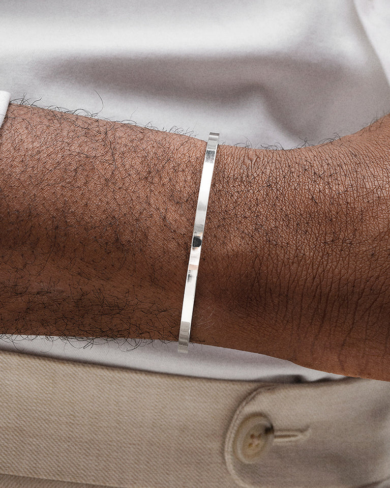 A polished stainless steel bangle in silver from Waldor & Co. One size. The model is Square Bangle Polished