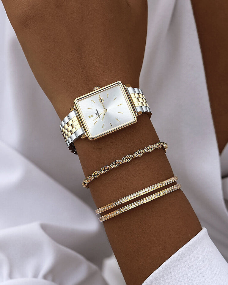 A square womens watch in silver and 14k gold from Waldor & Co. with silver sunray dial and a second hand. Seiko movement. The model is Delight 32 Chelsea 28x32mm.